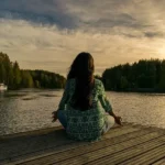 Vrouw zittend meditatie aan een meer