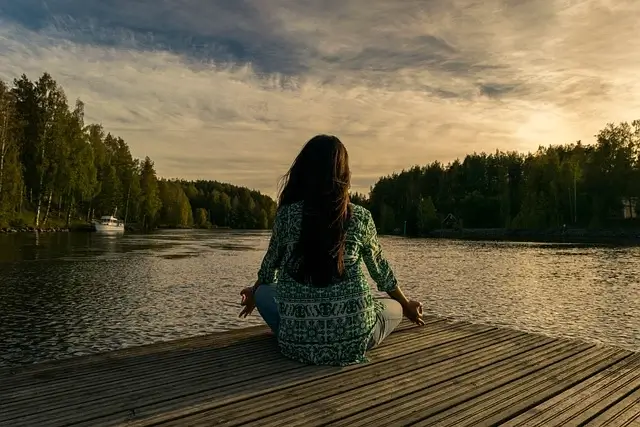Vrouw zittend meditatie aan een meer